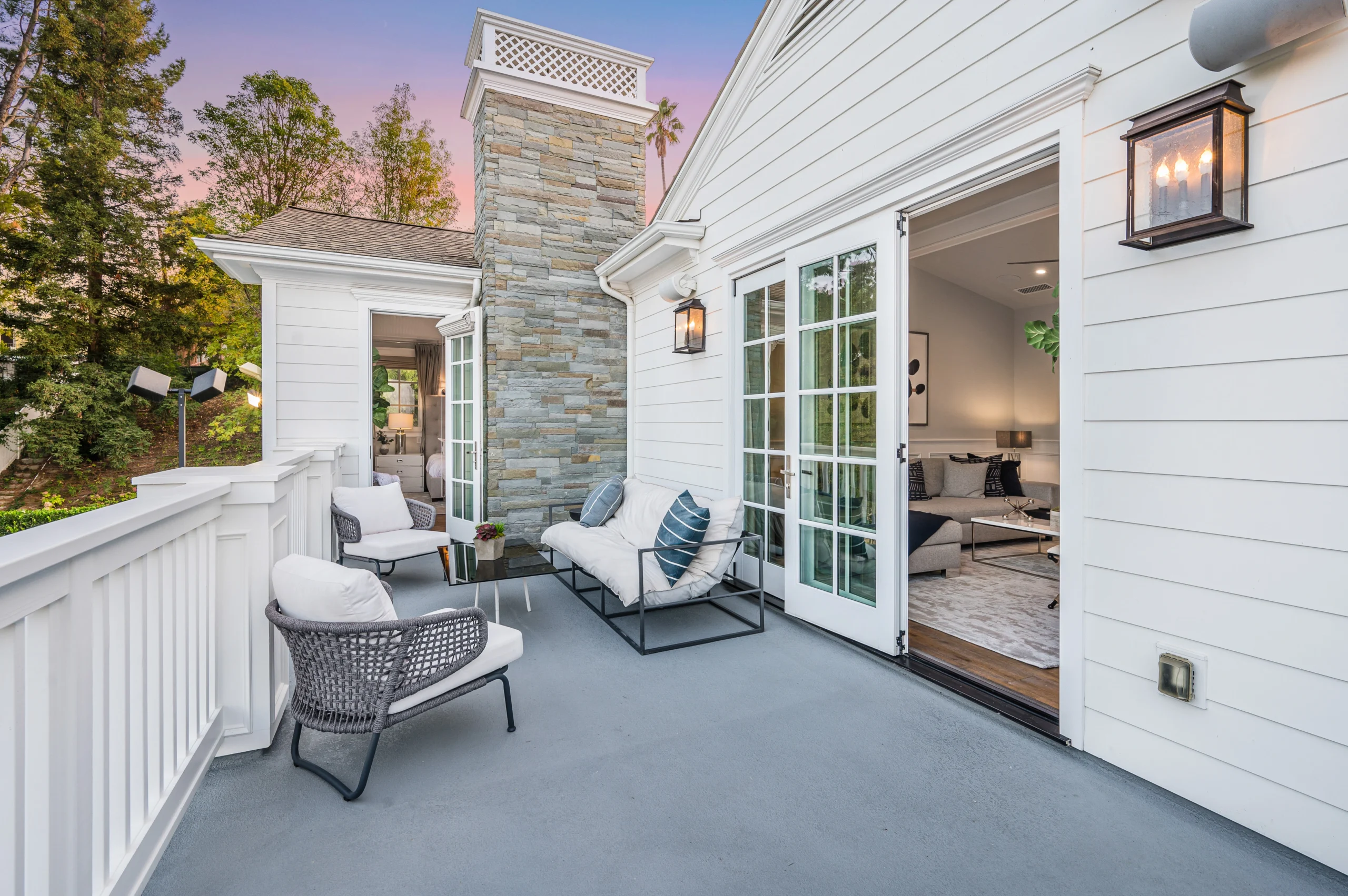 Luxury Hamptons balcony with outdoor seating area and stone chimney by Hamptons Luxury Design + Construction