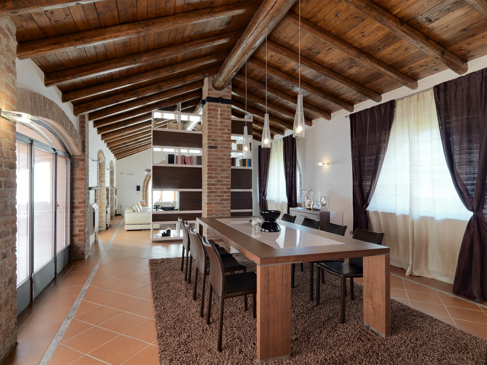 Rustic attic dining room with exposed wood beams and a long table after a luxury home remodel