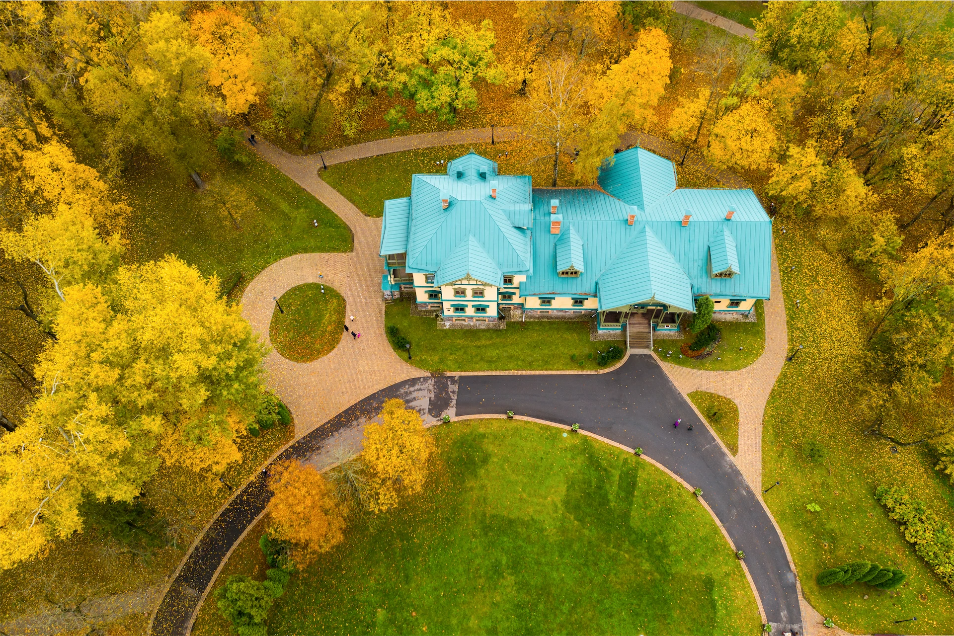 Aerial view of an expansive luxury residence surrounded by autumn trees, showcasing the scale and craftsmanship of a custom home builder