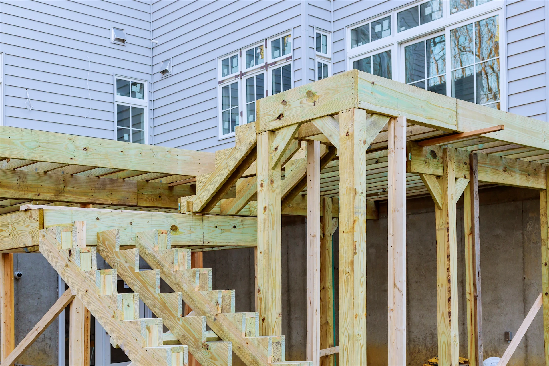 Home additions featuring new wood framing and exterior stairs being built onto an existing home