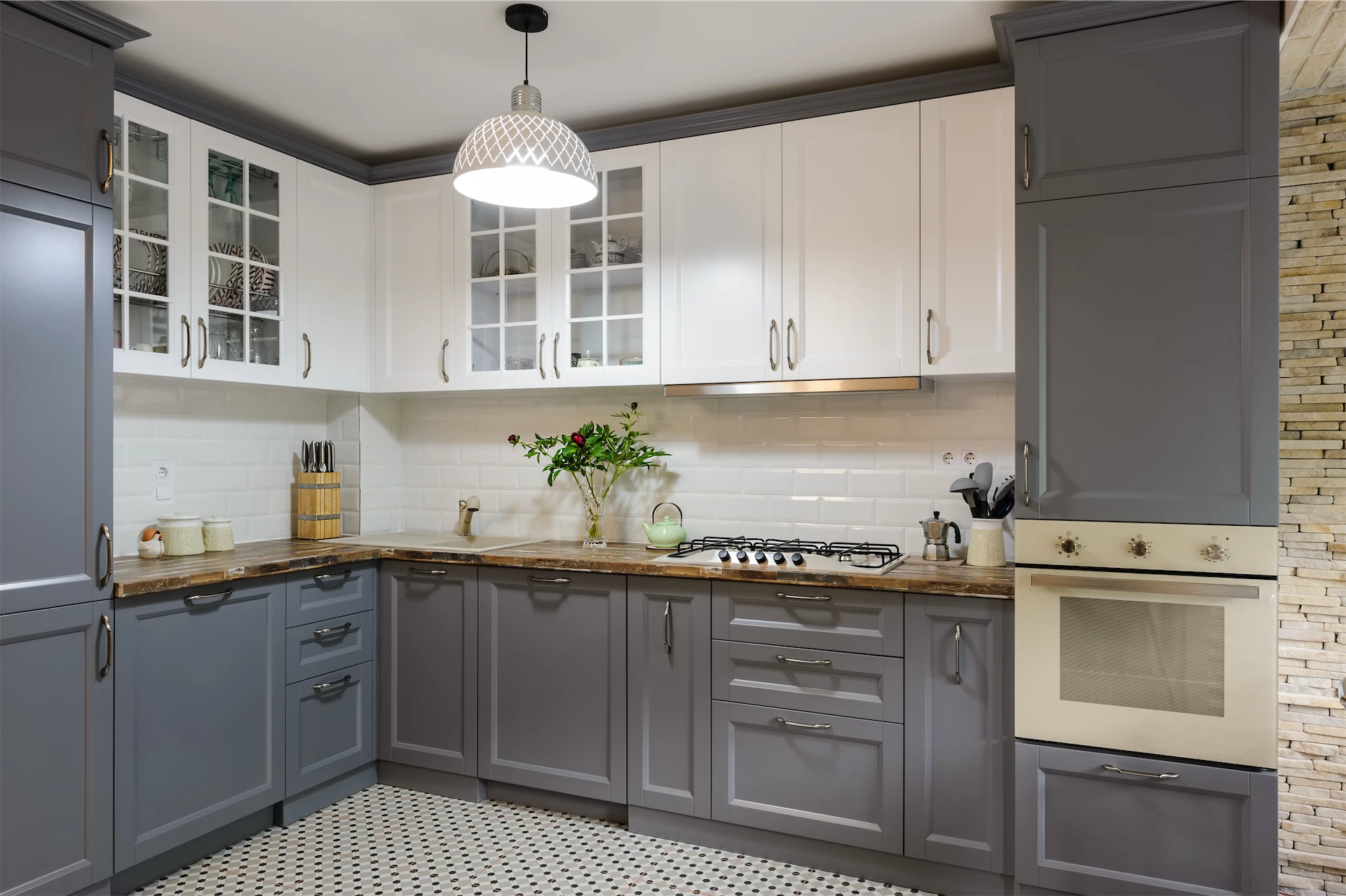 Kitchen renovation featuring gray and white cabinetry, stone countertops, built-in oven, and contemporary pendant lighting