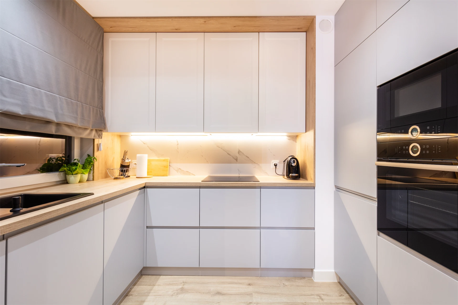 Kitchen renovation featuring white cabinetry, wood countertops, integrated appliances, and warm under-cabinet lighting