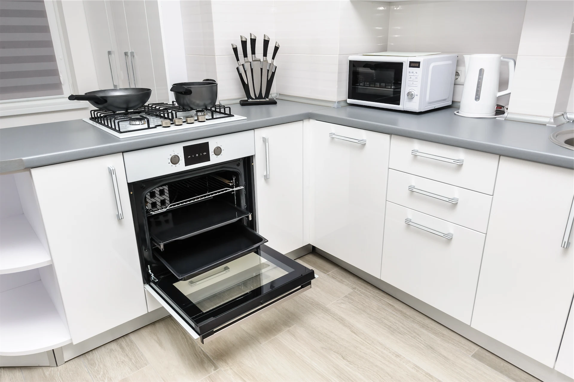 Kitchen renovation with white cabinetry, gray countertops, built-in oven, gas cooktop, and modern appliances