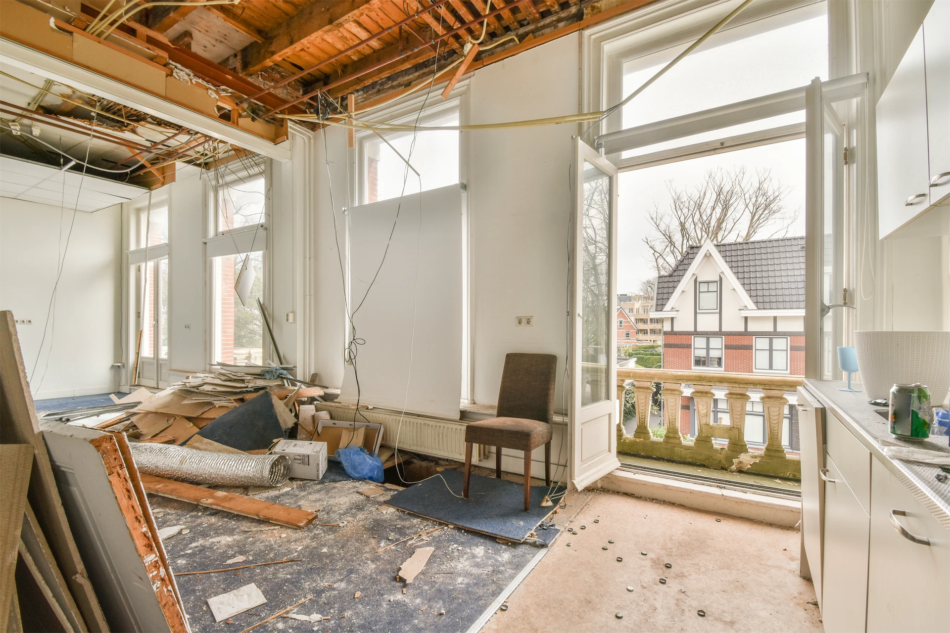 Luxury home renovation interior with exposed ceiling framing, electrical wiring, and ongoing demolition work
