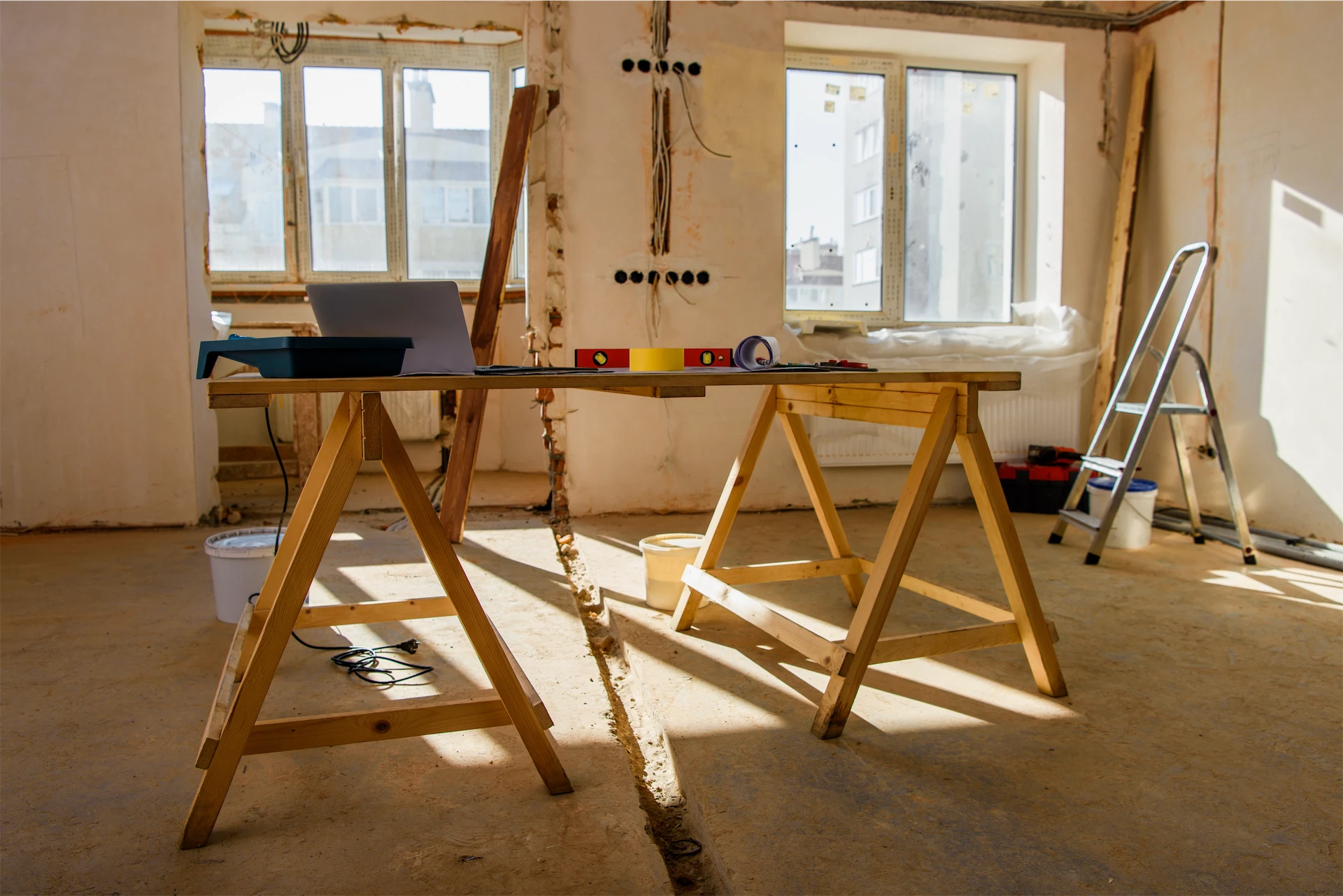 Luxury home renovation interior with workbench, ladder, tools, and exposed electrical wiring