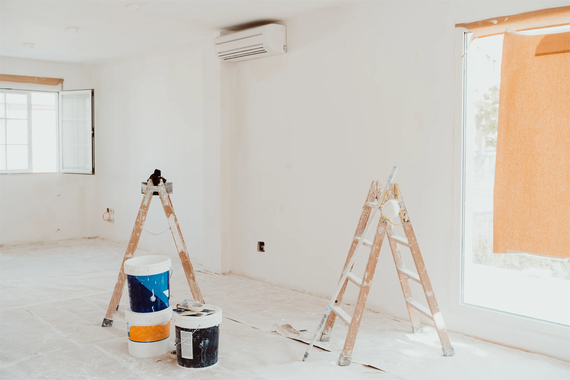 Luxury home renovation project with ladders, paint supplies, and unfinished interior walls