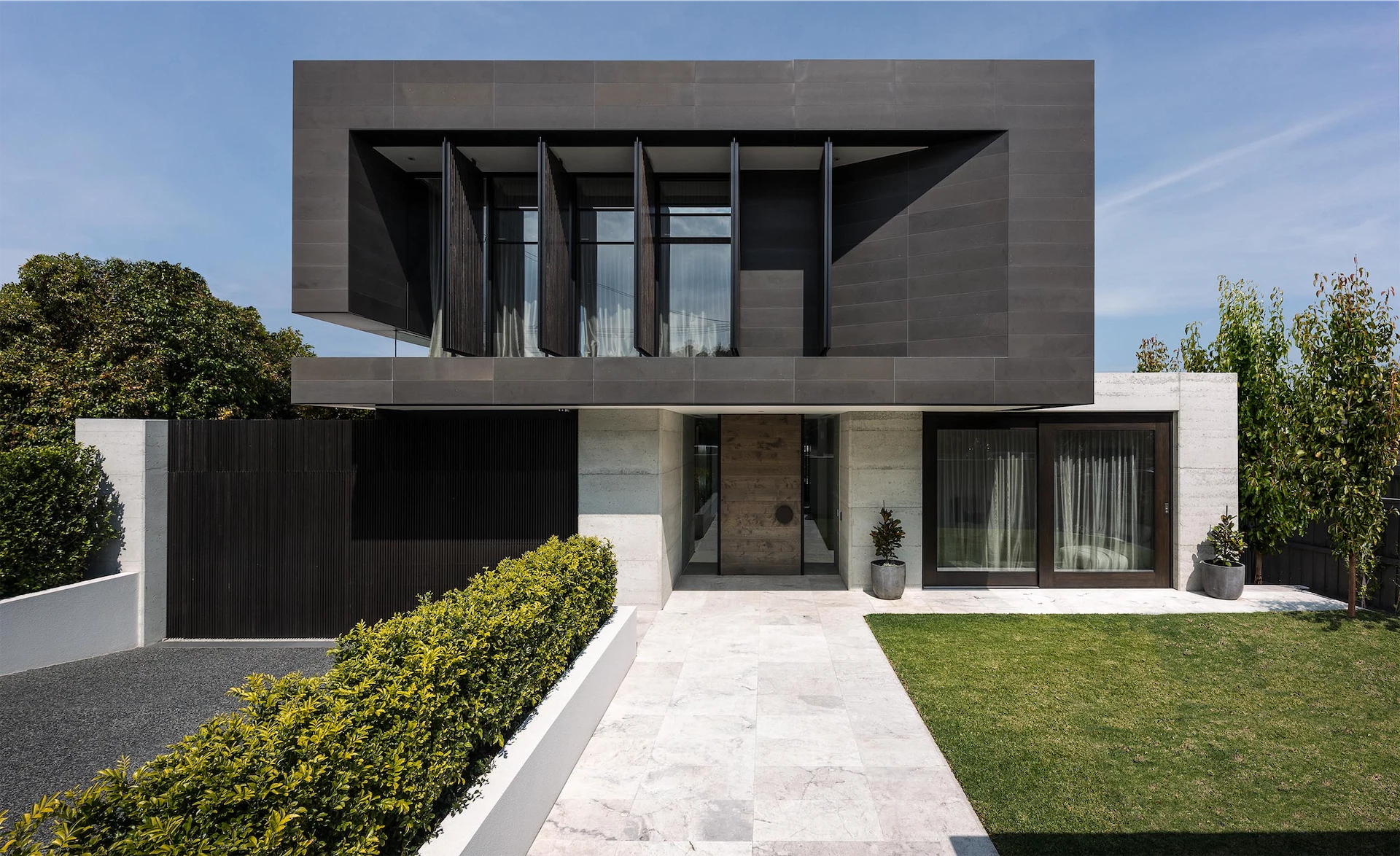 Modern luxury home exterior with bold architectural lines, large windows, and landscaped grounds completed by a custom home builder