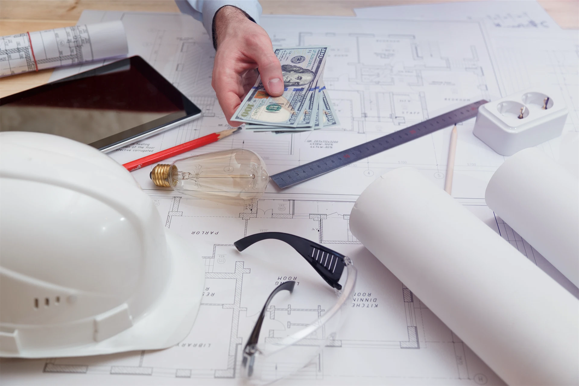 Preconstruction cost estimating and budgeting with blueprints, cash, and construction safety equipment